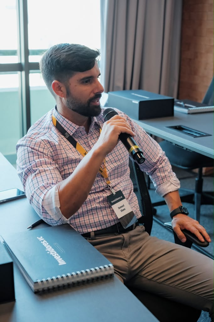 Sam Viana speaking into a microphone at an investor event